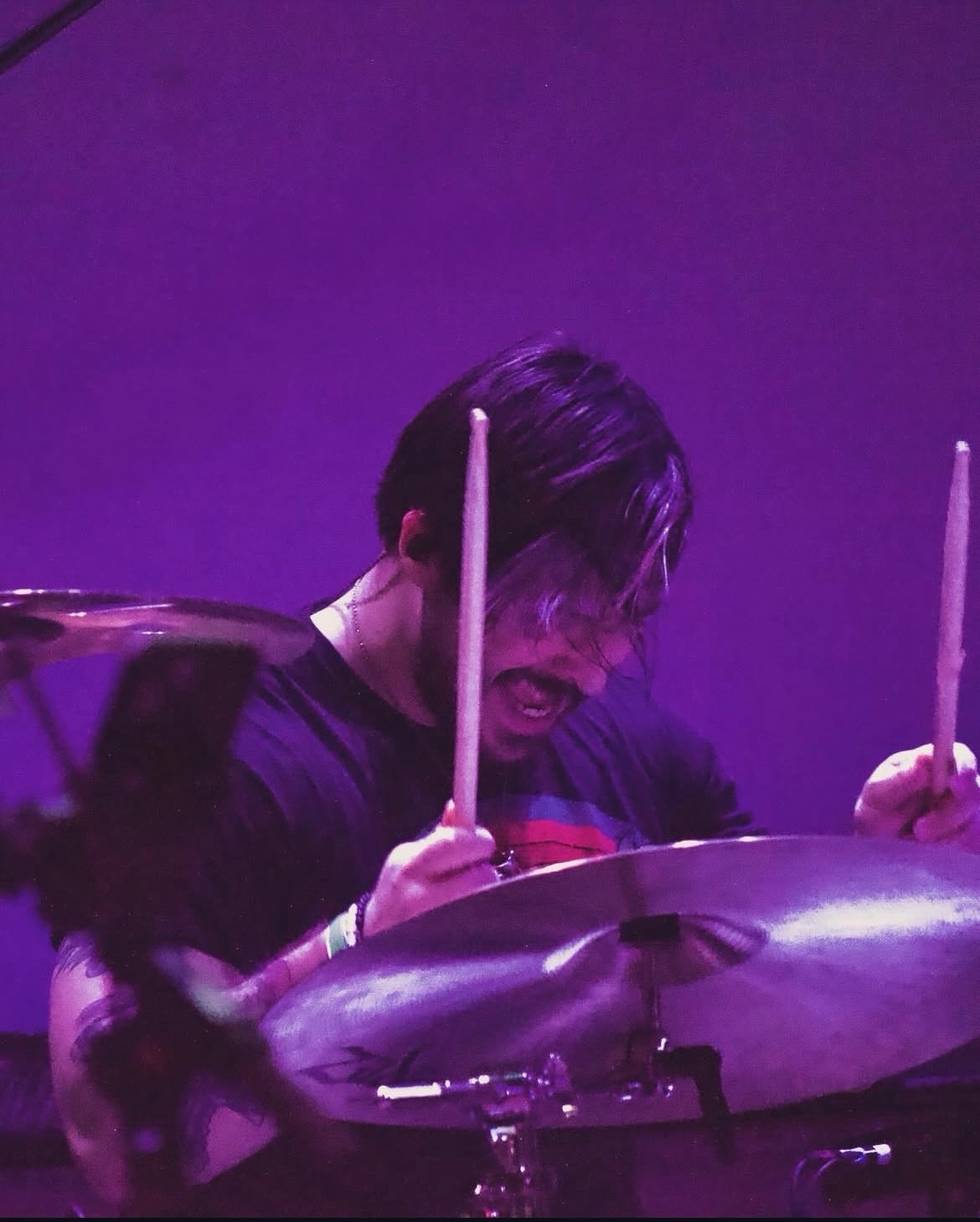 G2 playing drums under purple stage lights